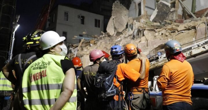 Lebanese and Chilean rescuers watching a crane at the site of a collapsed building after getting signals there may be a survivor buried in the rubble.