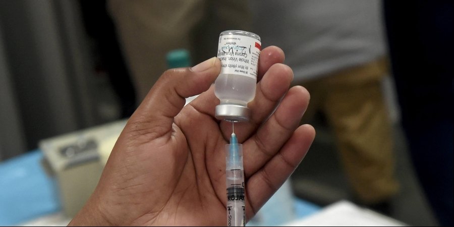 A medic prepares a dose of COVID vaccine in a syringe during a vaccination drive.